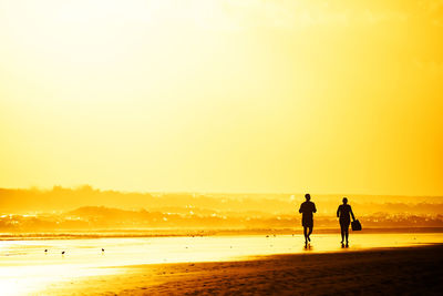 Tourists visiting beach against clear sky