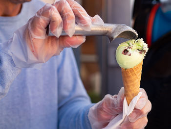 Midsection of man scooping ice cream cone