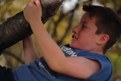 Side view of boy climbing tree