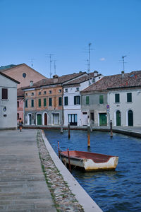 Boats in canal against clear blue sky