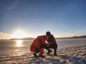 Woman and man stretching in winter  before run. two sports people working out on a lake in winter