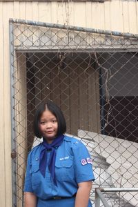 Portrait of a smiling young man standing against fence
