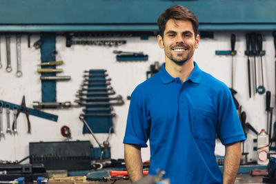 Portrait of young man standing against blue wall