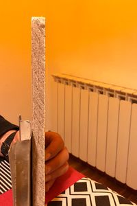 Close-up of hand holding railing against orange wall