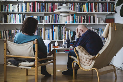 Depressed patient and female therapist in front of bookshelf at home office