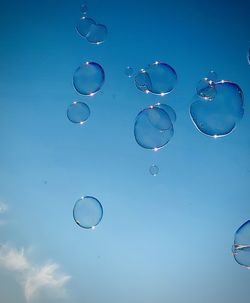 Low angle view of bubbles against blue sky