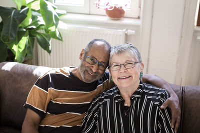 Smiling couple with arm around sitting on sofa at home