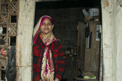 Portrait of smiling young woman standing at the door