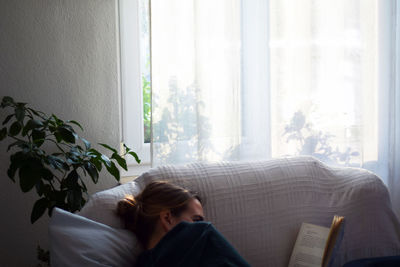 Woman reading book on sofa at home