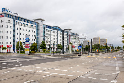 Road by buildings against sky in city