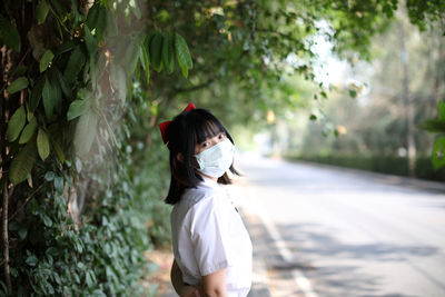 Rear view of woman standing against trees