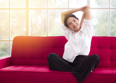 Smiling young woman sitting on sofa