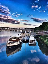 Boats moored on river in city against sky