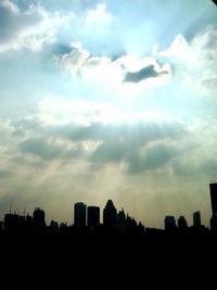 Silhouette of buildings against cloudy sky at sunset