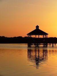 Silhouette gazebo in lake against sky during sunset