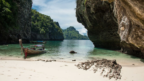 Boat moored on shore by rock formations