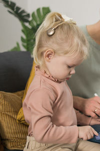 High angle view of cute baby girl sitting on bed at home