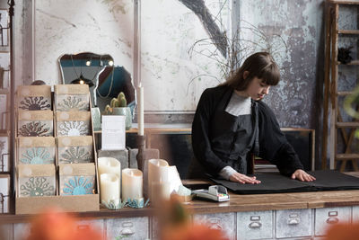 Confident young female owner looking at wrapping paper on counter in store