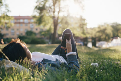 Teenage girl using smart phone while lying on grass