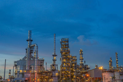 Low angle view of illuminated factory against sky