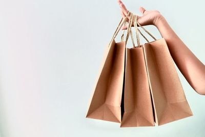 Low angle view of man holding paper hanging against white background