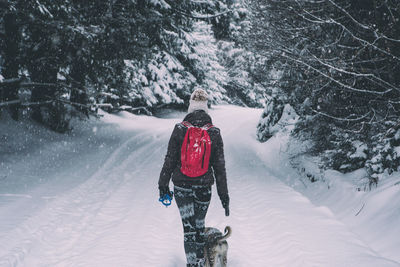 Rear view of woman on snow covered path among trees