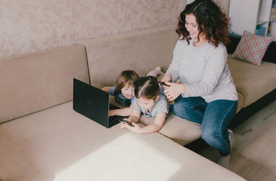 High angle view of woman using phone while sitting on floor