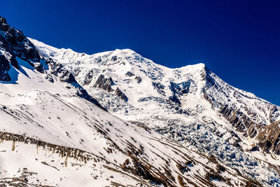 Scenic view of snowcapped mountains against clear blue sky