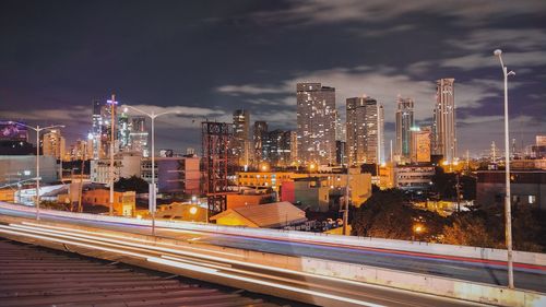 Illuminated modern buildings in city against sky at night