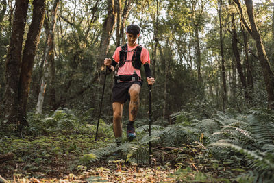 Man traveler with trekking poles walking up old stone stairs in jungles