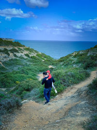 Rear view of man on sea shore against sky