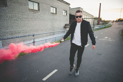 Full length portrait of young man with smoke bomb