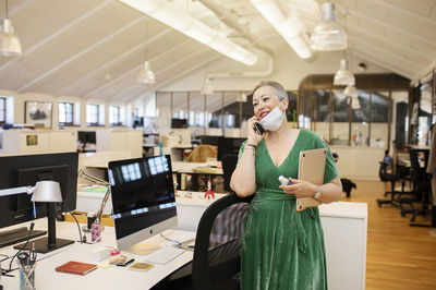 Woman in office talking via cell phone