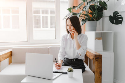 Full length of woman using phone on table