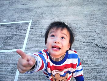 Cute boy looking up while pointing on footpath