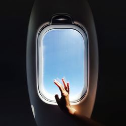 Close-up of hand on window in airplane