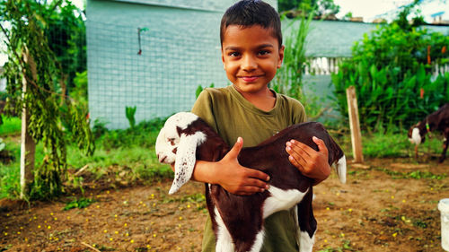 Indian little boy holding the small goat. friendship of child and yeanling, image toned.
