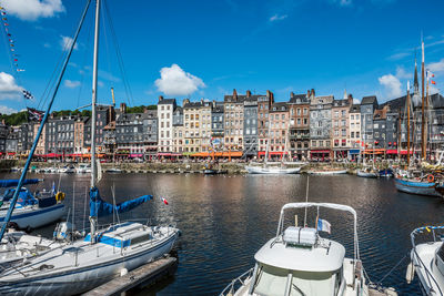 Boats moored at harbor against buildings in city