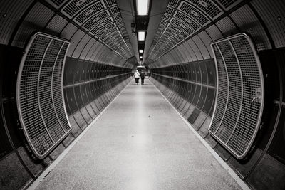 Rear view of women walking in illuminated tunnel