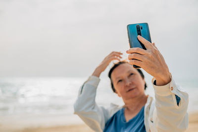 An adult woman on the beach near the ocean in the spring at a picnic takes a selfie, talks a video