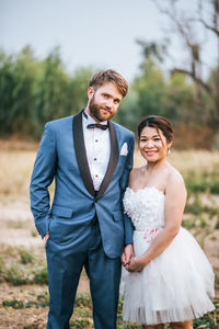 Portrait of smiling newlywed couple on field