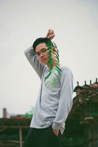 Portrait of young man holding leaf while standing outdoors