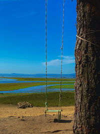 View of swing on beach against blue sky