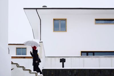 Man standing by building against sky