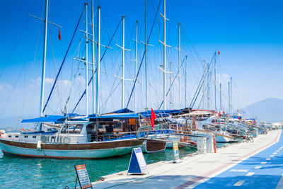 Sailboats moored in harbor against clear blue sky