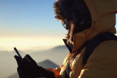 Close-up of hiker using phone on mountain against sky