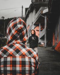 Rear view of people walking on street against buildings in city