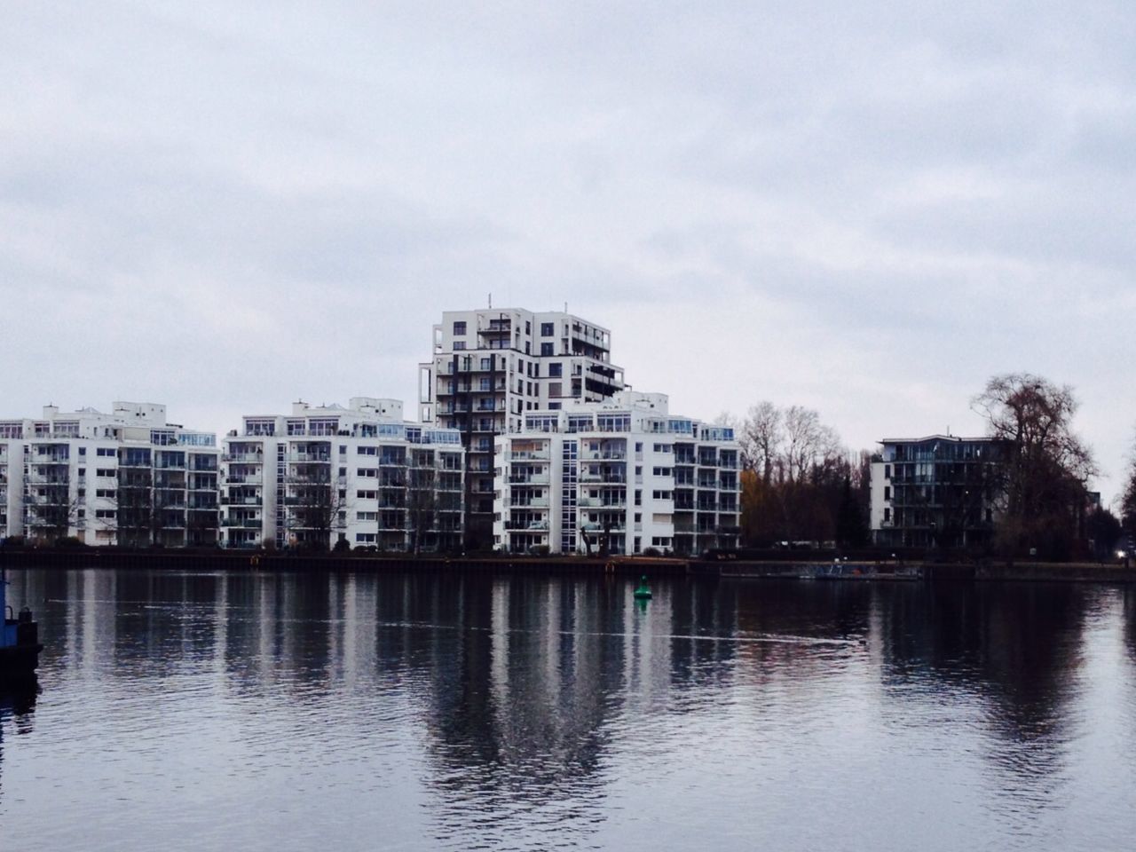 building exterior, architecture, built structure, water, waterfront, sky, city, reflection, river, building, residential building, lake, residential structure, cloud - sky, day, outdoors, no people, cloud, rippled, cityscape