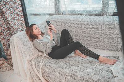 Young woman using mobile phone while sitting on floor