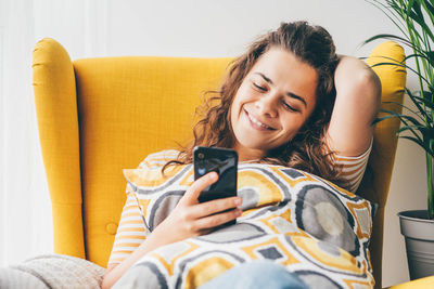 Low section of woman sitting on sofa at home